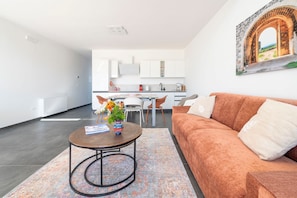 Un salon moderne avec un canapé, une table basse et une vue sur la cuisine et la salle à manger.