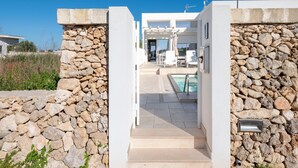 A modern house with a stone wall entrance, a pool, and a patio area with outdoor furniture. - Villa 'Venza , Salento' with Sea View, Wi-Fi and Air Conditioning (Otranto)