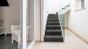 A modern interior with a staircase, a glass door, and a white wicker chair. - Villa 'Venza , Salento' with Sea View, Wi-Fi and Air Conditioning (Otranto)