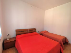 Camera da letto con due letti, un comodino, una lampada e una testiera in legno.