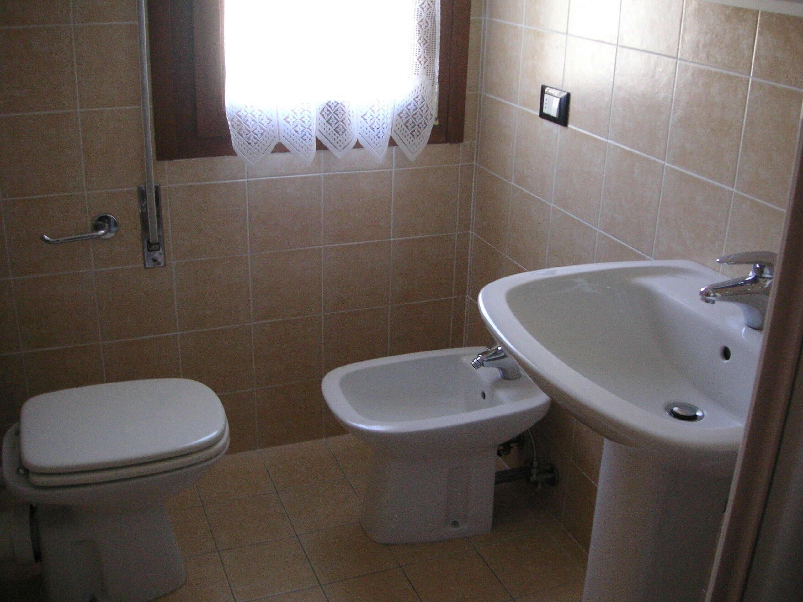 A bathroom with a toilet, bidet, and sink.