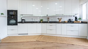 A modern kitchen with white cabinets, a black microwave, a coffee machine, and a wooden floor. - Villa 'Casa Ohana' with sea views, Wi-Fi, and air conditioning (Fuengirola)