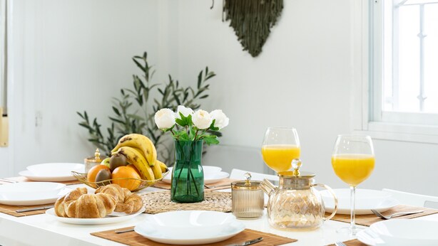 A breakfast table with croissants, fruit, a vase with flowers, and two glasses of orange juice. - Villa 'Casa Ohana' with sea views, Wi-Fi, and air conditioning (Fuengirola)