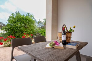 Een buitentafel met een boek, druiven, een wijnfles en een mand.