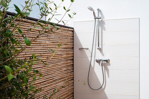 A shower with a bamboo wall and a white panel.
