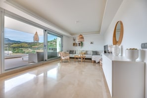 A spacious living area with a balcony, a sofa, a coffee table, and a dining table.