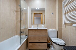 Ein Badezimmer mit Badewanne, Toilette, Waschbecken und Spiegel.