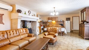 Un salon comprenant un canapé, un fauteuil et une table basse, une cuisine avec des meubles en bois et une cheminée.