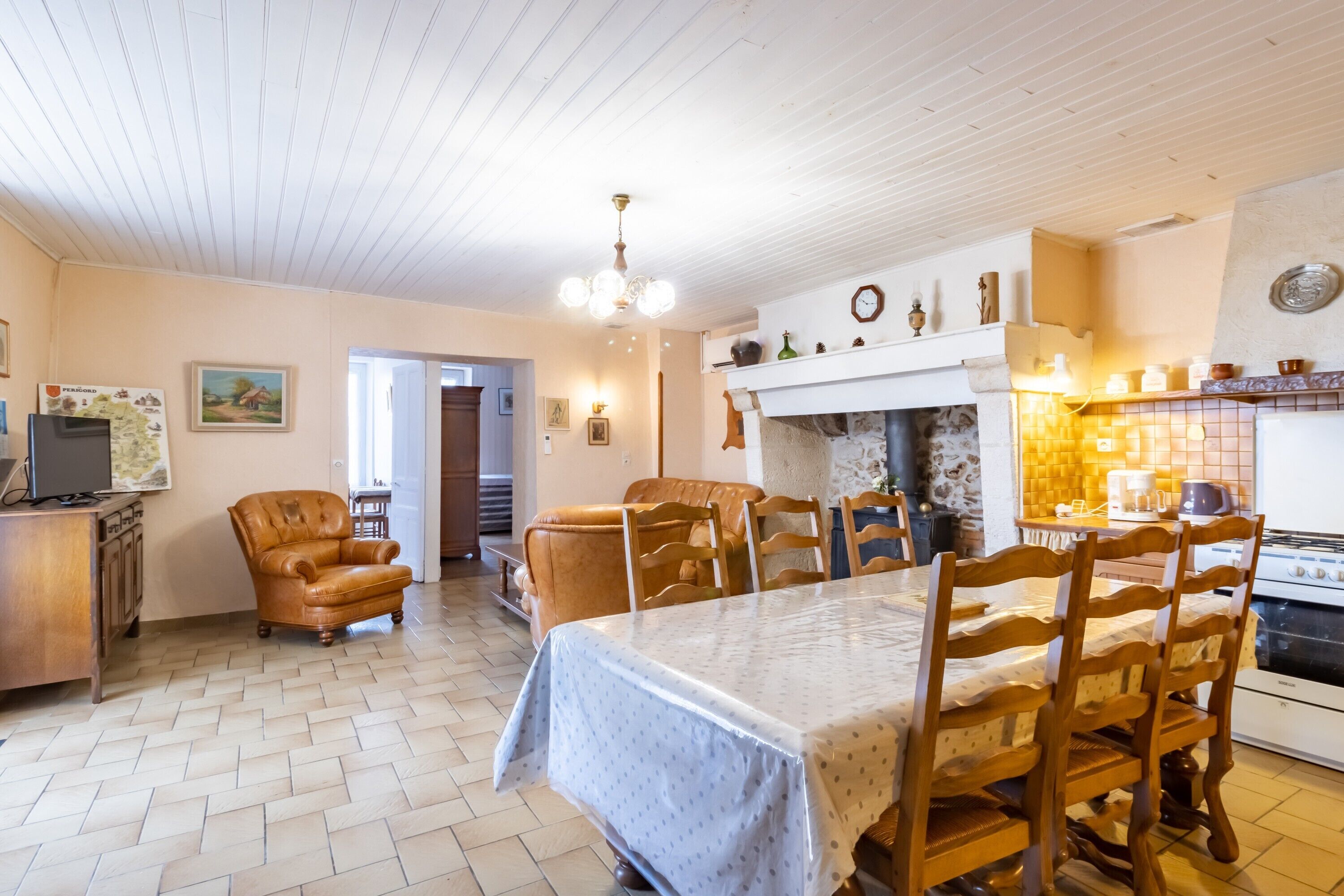 Zona pranzo con tavolo e sedie in legno, camino e angolo cottura con piano cottura.