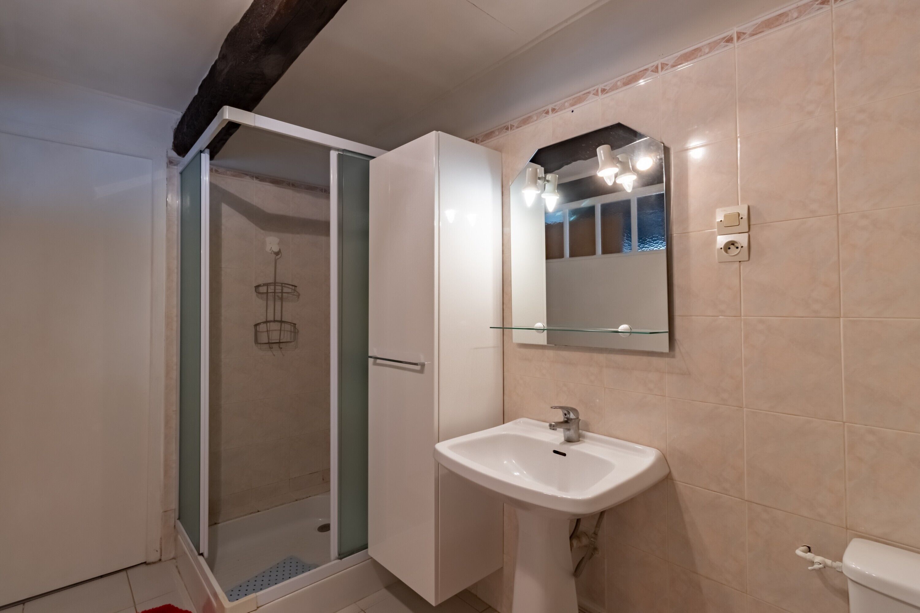 Un bagno con cabina doccia in vetro, lavandino bianco, specchio e WC.