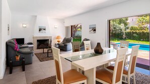 Ein modernes Wohnzimmer mit einer Couch, einem Esstisch mit Glasplatte und einem Kamin.