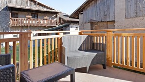 Ein Balkon mit Korbmöbeln, Holzbalkonen und Blick auf rustikale Gebäude.