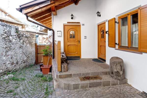 A stone wall, wooden door, steps, and a mailbox.