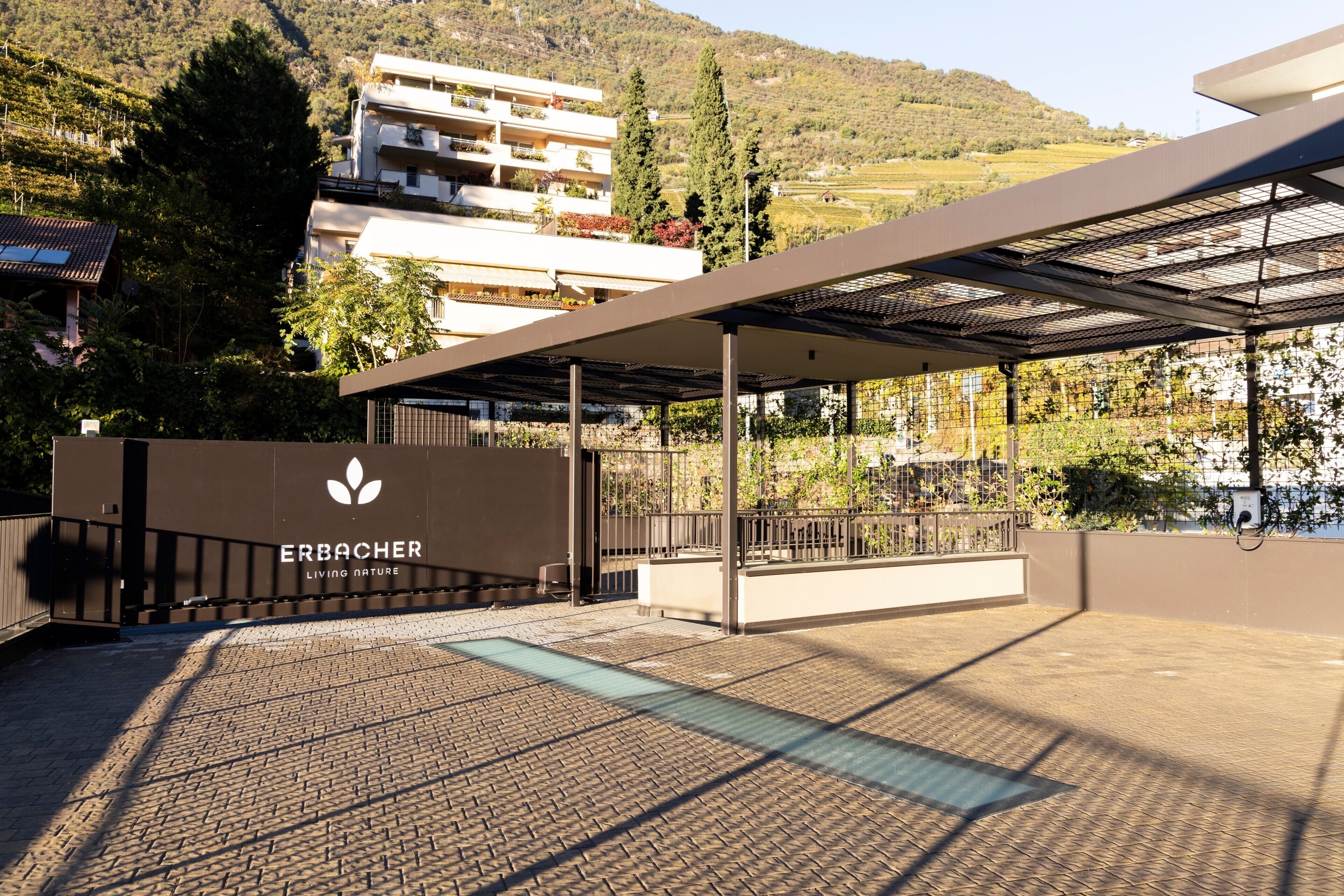 A covered outdoor area with a modern design, a logo, and a view of a hillside.