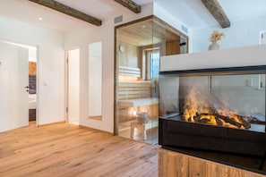 Un intérieur moderne avec une cheminée, un plancher en bois et une cloison en verre.