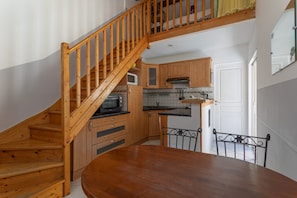 A kitchen with wooden cabinets, a microwave, and a dining table with chairs. - Holiday Home 1 with Mountain View, Air Conditioning (Reynes)