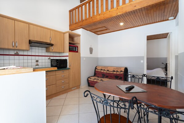 Una cocina con armarios de madera, un microondas y un comedor con mesa y sillas.