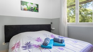 A bed with a floral-patterned bedspread, a dark headboard, and a window with a view of trees. - Holiday Home 4 with Mountain View, Shared Pool (Reynes)