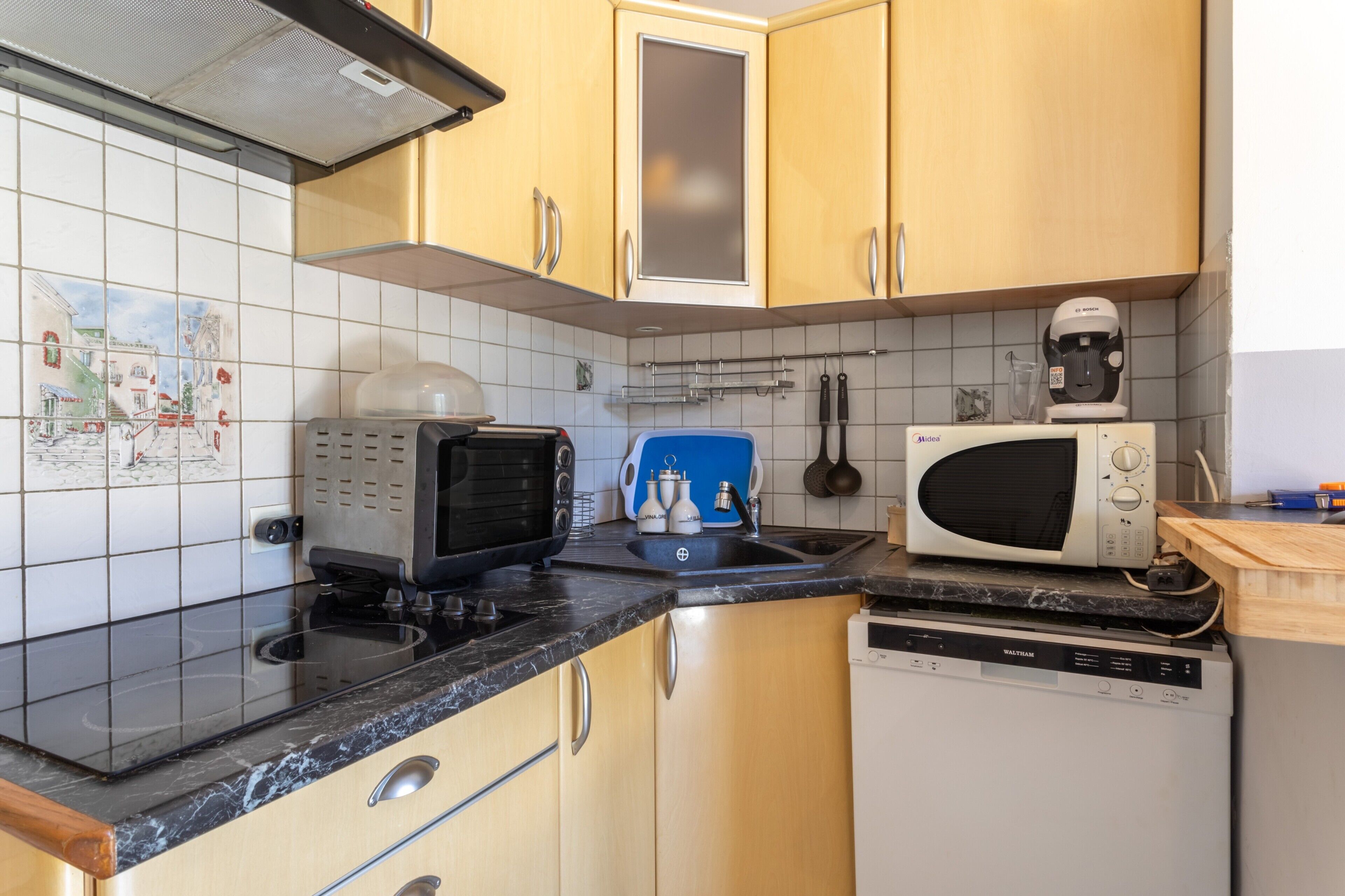 Een keuken met een magnetron, broodrooster en vaatwasser.