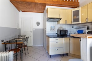 A compact kitchen with a dining table, chairs, a built-in oven, and a microwave.