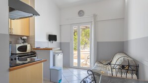 A compact kitchen with a microwave, toaster, and stove, a small refrigerator, a television, and a sliding glass door leading to an outdoor area. - Holiday Home 4 with Mountain View, Shared Pool (Reynes)