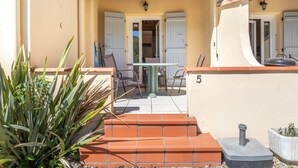 A patio with a table and chairs, a small garden, and a number '5' on the wall.