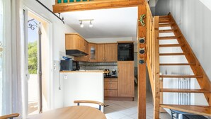 Een keuken met houten kastjes, een centraal eiland en een trap naar een hoger niveau.