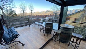 A balcony with a sofa, two bar stools, and two large barrels. - Large family country house in Rascafría,1 h from Madrid, 12 to 24 people (Rascafría)