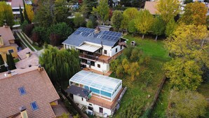 A two-story house with a large solar panel array on the roof and a glass greenhouse structure at the front. - Large family country house in Rascafría,1 h from Madrid, 12 to 24 people (Rascafría)