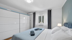 Et soveværelse med seng, et natbord, en garderobe og et vindue med gardiner.