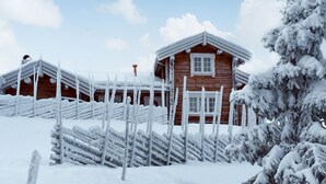 Een houten hutje met een sneeuwbedekte dak en een houten hek.