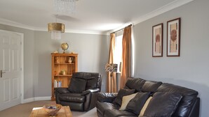 A living room with a leather sofa, a wooden coffee table, a leather armchair, a wooden bookshelf, and a chandelier. - 4 bedroom accommodation in Boston (Boston)