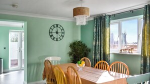 A dining room with a wooden table, chairs, a clock, and a window with curtains. - 4 bedroom accommodation in Boston (Boston)