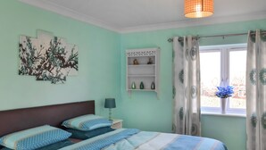 A bedroom with a bed, a nightstand, a lamp, a window with curtains, and wall art. - 4 bedroom accommodation in Boston (Boston)