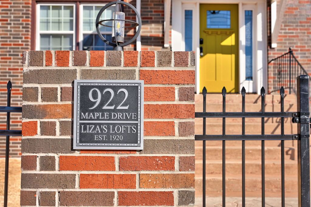 A brick wall with a sign reading "922 Maple Drive, Liza's Lofts, Est. 1920."