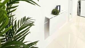 A modern living room with a mounted TV displaying various streaming services, a white console table, and a potted plant. - Luxurious Blue Studio! The Keys, Everglades, Biscayne N. Park, Redlands & Miami (Florida City)