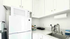 A kitchen with white cabinets, a stainless steel sink, and a white refrigerator. - Luxurious Blue Studio! The Keys, Everglades, Biscayne N. Park, Redlands & Miami (Florida City)