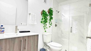 A modern bathroom with a wooden vanity, a toilet, a shower enclosure, and a mirror. - Luxurious Blue Studio! The Keys, Everglades, Biscayne N. Park, Redlands & Miami (Florida City)