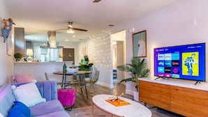 A modern living room with a sofa, coffee table, and a flat-screen TV displaying a streaming service interface. - Southtown 3BR Pool & Playset—Riverwalk—BBQ—Firepit (San Antonio)
