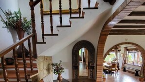 Amplia sala de estar con escalera de madera, un banco y un espejo grande.