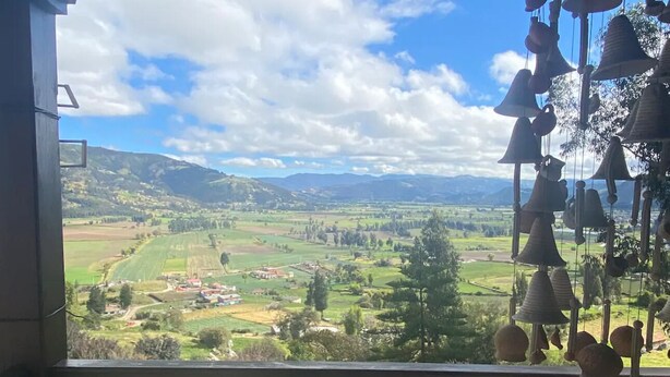 Un balcón con vistas a un paisaje rural, que incluye campos y montañas distantes.