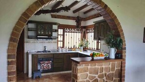 Una cocina con una isla de piedra, un arco de ladrillo y una lámpara colgante.