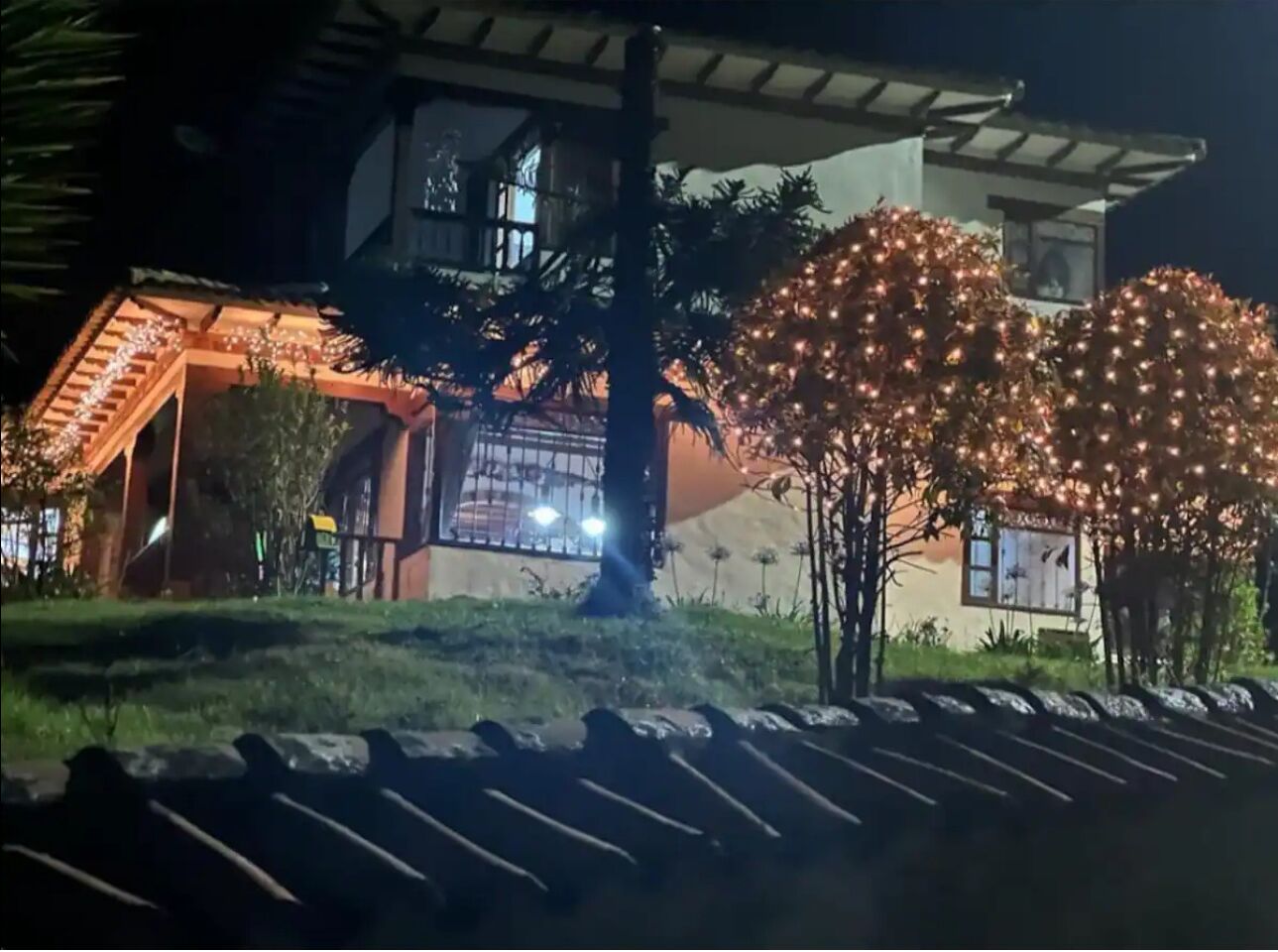 A building with a covered outdoor area and a tree decorated with lights.
