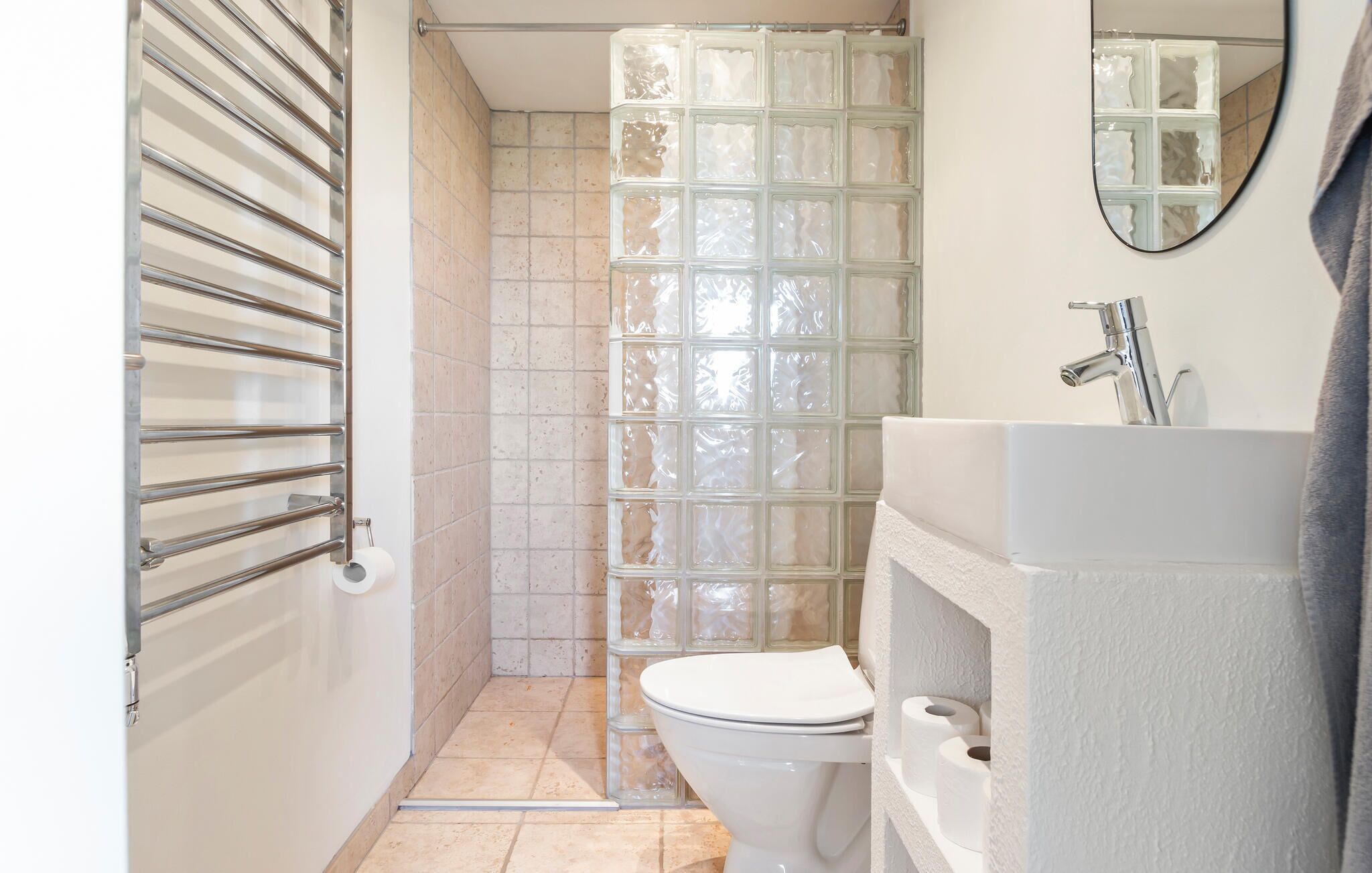 Une petite salle de bain comprenant des toilettes, une douche à parois de verre et un lavabo avec un miroir.