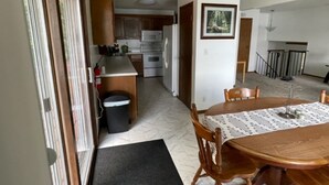 A kitchen with wooden cabinets, a microwave, and a refrigerator. There is a dining table with chairs and a mat in front. - Private Lake House on Pokegama in northern MN. For any occasion all year round. (Grand Rapids)
