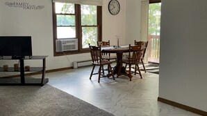 A dining area with a wooden table and chairs, a clock on the wall, and a TV on a stand. - Private Lake House on Pokegama in northern MN. For any occasion all year round. (Grand Rapids)