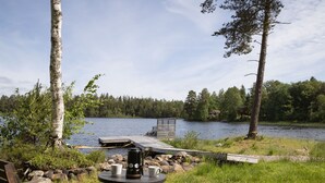Ein Sitzbereich im Freien am Seeufer mit Tisch, Stühlen und einer Kaffeekanne.
