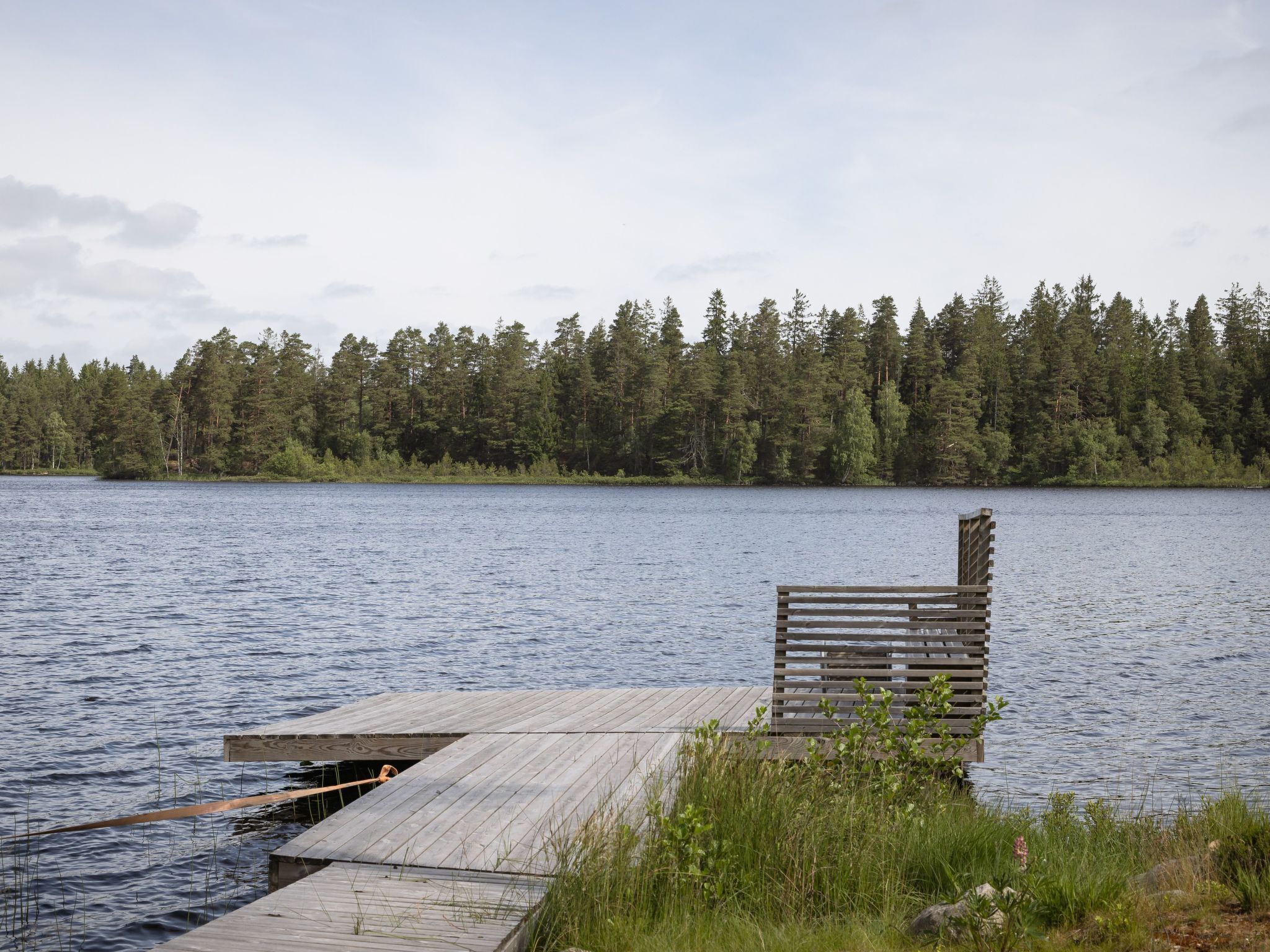 Eine hölzerne Anlegestelle, die in einen See hineinreicht, umgeben von dichtem Wald.