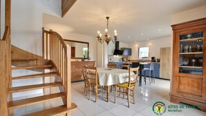 Une cuisine spacieuse avec un coin repas, un escalier en bois et un lustre.