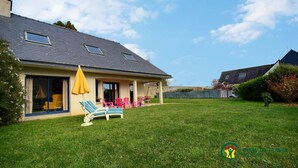 Une maison dotée d’un patio couvert, d’une pelouse et d’un espace salon extérieur.